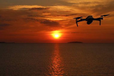 Gün batımında gökyüzünde uçarken drone'lar, Okyanus ve ada arka