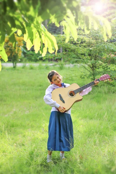 Asian school girl playing the guitar on the lawn , Student learn — Stock Photo, Image