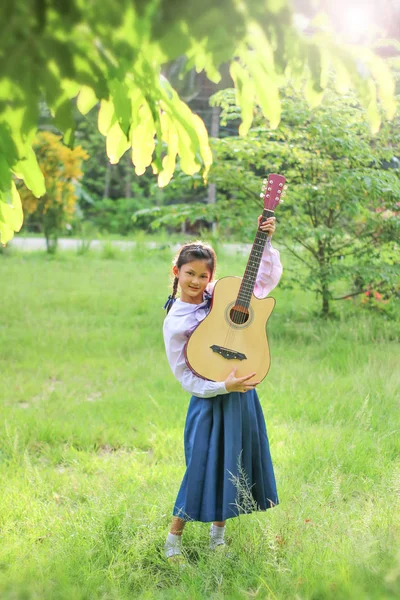 Asian school girl playing the guitar on the lawn , Student learn — Stock Photo, Image