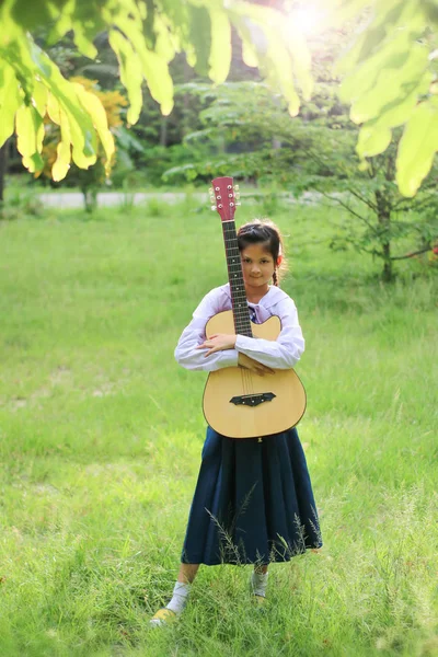 Asian Szkoła dziewczyna gra na gitarze na trawniku, Student uczyć się — Zdjęcie stockowe