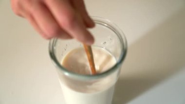 Kapalı el, zemin sıvısıyla sütü bardakta tahta kaşıkla karıştırıyor. Hamur işi, fırın ve yemek pişirme konsepti