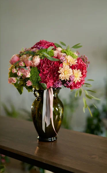 Taze pembe güller, bej kasımpatılar, altın papatyalar, kırmızı ortancalar, yeşil boğaz otu, balmumu çiçekleri ve çiçekçide okaliptüsler.