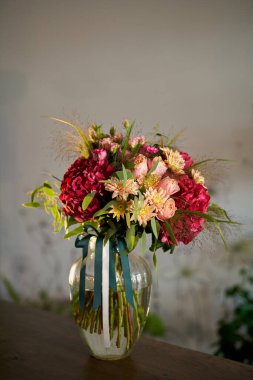 Çiçekçide cam vazoda çiçek buketi. Kırmızı ortancalar, sarı kasımpatılar, taze çiçek konsepti olarak pembe güller.