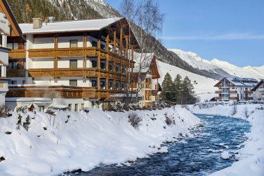 Ischgl, Avusturya - 29 Aralık 2017: Küçük dağ dere Tyrol Alpleri'nde. Dağ Nehri yakınında bir ahşap ev kar ile kaplı.