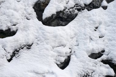 Taze kar - arka plan dokusu ile dikey dağ yamacı taşlarla kaplı