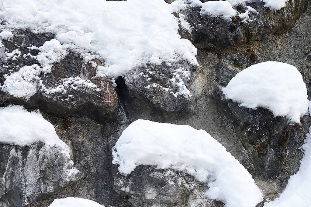 Vertical hill slope with rocks covered with snow