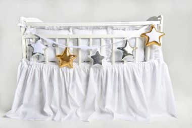 Gümüş, altın ve beyaz yıldız şekilli yastıklar üzerinde beyaz Bebek karyolası