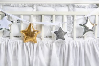 Gümüş, altın ve beyaz yıldız şekilli yastıklar üzerinde beyaz Bebek karyolası 