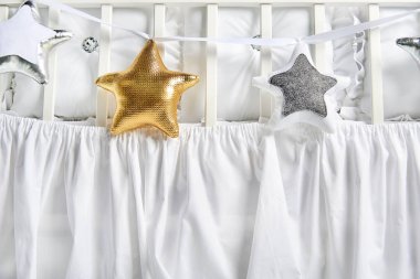 Gümüş, altın ve beyaz yıldız şekilli yastıklar üzerinde beyaz Bebek karyolası 