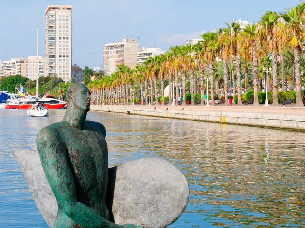 Statue of Icarus in the water. In the background a beautiful promenade in Alicante. Spain.