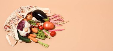 Bej arka planda taze sebzelerle dolu bir torba.