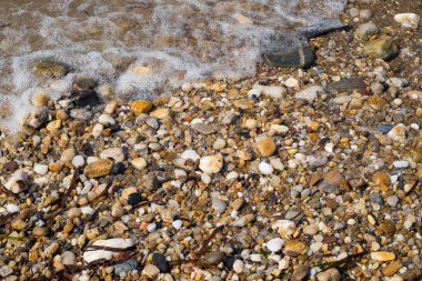 Dalga deniz ya da okyanus kıyısında çakıl.