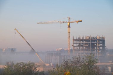 Sisli sabah İnşaat vinçleri kullanarak çok öykülü bir bina inşaatı görünümünü.