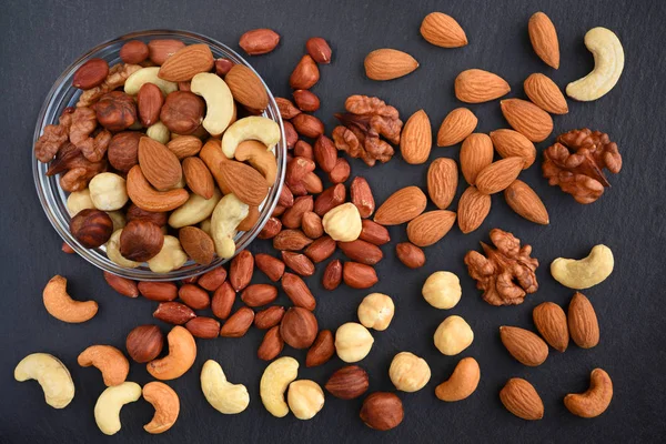 Assortment of nuts on a black slate background top view. Concept healthy snack.