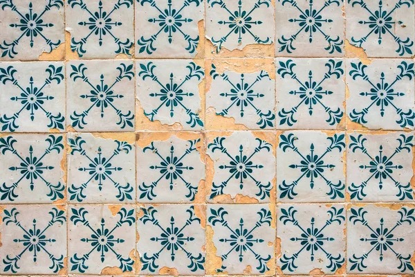 Old cracked wall with traditional Portuguese decor tiles azulezhu in blue tones.