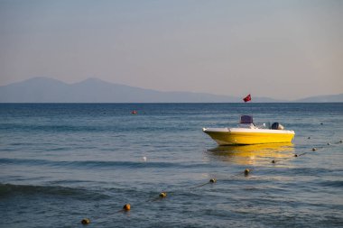 Arka plan mavi gökyüzünün altında kayalık kıyılarının Türkiye bayrağı denize boş kurtarma sarı tekne.