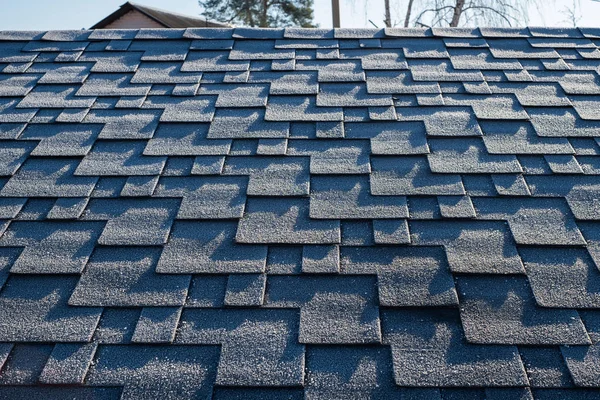 Close up view on asphalt roofing shingles covered with frost