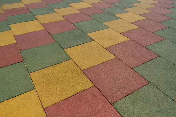Colored rubber square paving slab for playgrounds close-up.
