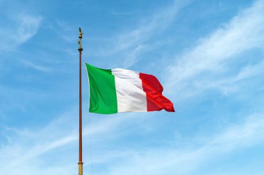 Mavi gökyüzüne karşı rüzgarda çırpınan bayrak direğinde İtalya bayrağı.