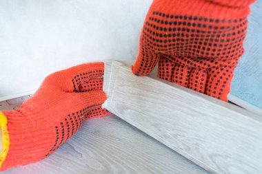 Laminat parke üzerinde Işçi elleri Instal plastik süpürgelik kurulu. Evde taban tahtası nın yenilenmesi.