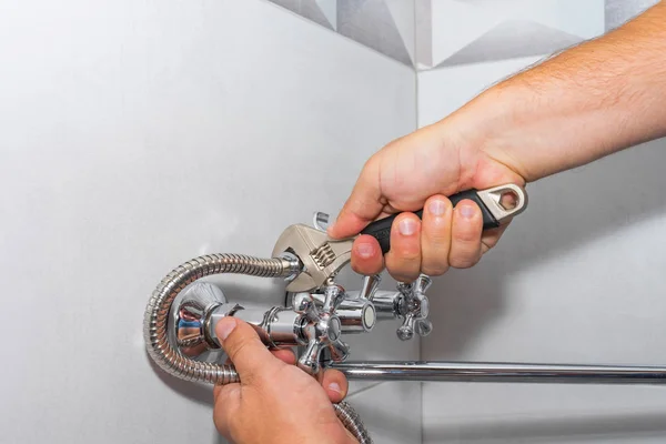 Plumber repairs a shower faucet in the bathroom.