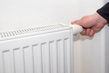 Erkek el evde soğuk bir sezon ile beyaz ısıtma radyatör üzerinde termostat kolu düzenler.