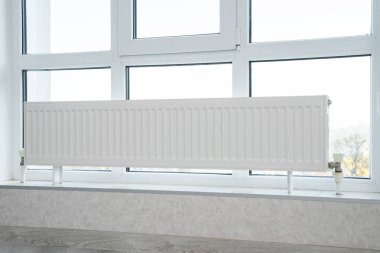 Bir apartmanın penceresinin önündeki ısıtma radyatörü..