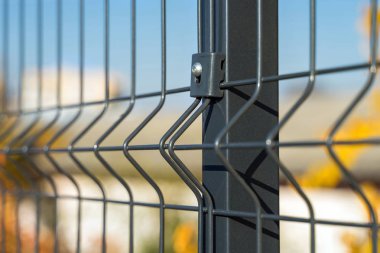 Mavi gökyüzü arkaplanındaki tel örgülerden yapılmış çelik parmaklıklar. Kısmi eskrim kurulumu