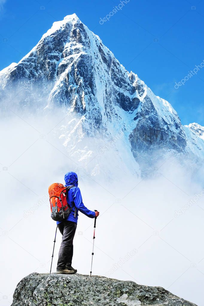 Hiker with backpacks reaches the summit of mountain peak. Success freedom and happiness achievement in mountains. Active sport concept.