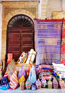 Fas el yapımı el sanatları, halı ve çanta seçici odak ile Fas Essaouira dar sokakta asılı