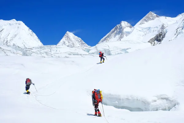 登山者爬上了山顶. 冰川上有三个登山者 成功，自由，幸福，在山上的成就。 攀爬运动概念. — 图库照片