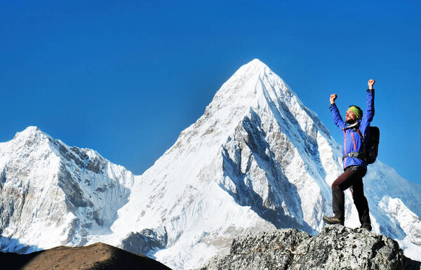 Hiker with backpacks reaches the summit of mountain peak. Success freedom and happiness achievement in mountains. Active sport concept.