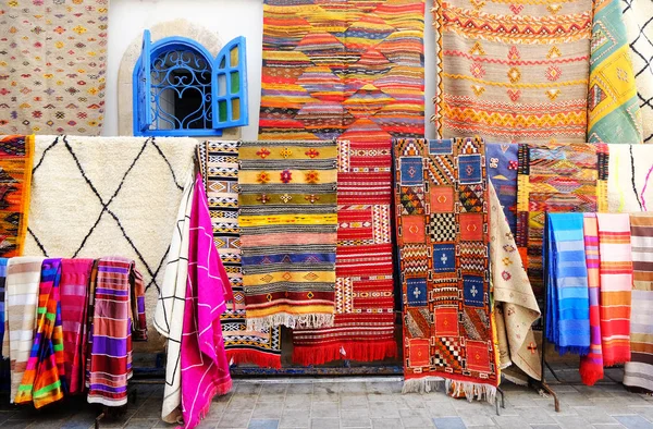 Artesanato artesanal marroquino, tapetes e sacos pendurados na rua estreita de Essaouira, em Marrocos, com foco seletivo — Fotografia de Stock