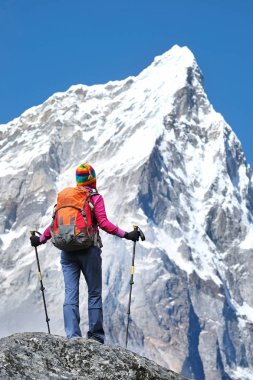 Genç kadın dağcı, panoramik manzaranın keyfini çıkarırken dağ zirvesinin zirvesine ulaşır. Başarı, özgürlük ve mutluluk, dağlarda başarı. Tırmanma sporu konsepti.