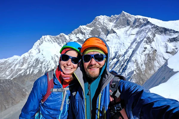 Two climbers reaches the summit of mountain peak.  Success, freedom and happiness, achievement in mountains. Climbing sport concept.