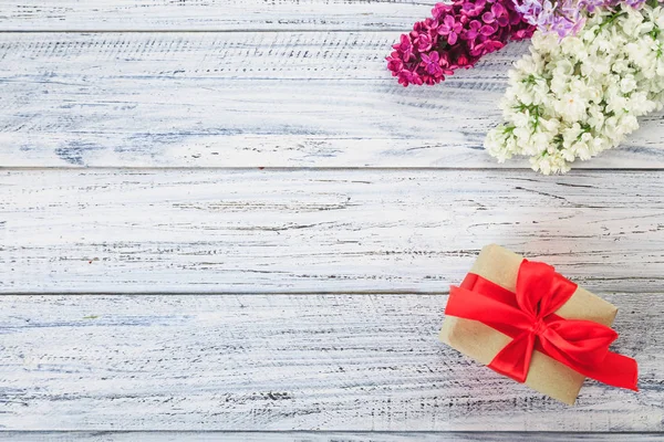 Подарок и цветы на деревянном фоне — стоковое фото