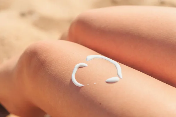 Sunscreen in the form of heart on female leg — Stock Photo, Image