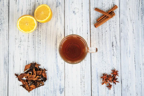 Tasse de thé, citron, cannelle, clous de girofle, feuilles de thé séchées — Photo