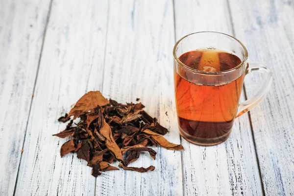Tasse de thé noir et feuilles de thé — Photo