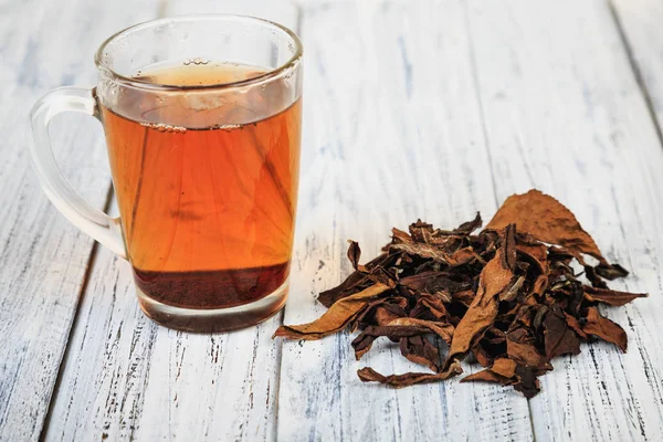 Tasse de thé noir et feuilles de thé — Photo