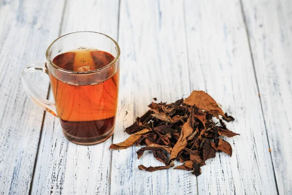 Tasse de thé noir et feuilles de thé — Photo