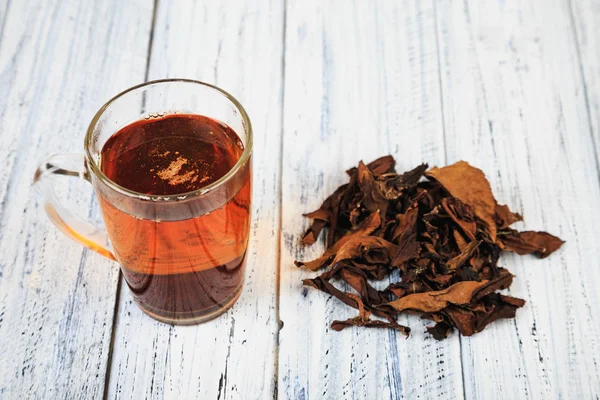 Tasse de thé noir et feuilles de thé — Photo