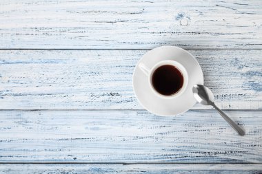 Gri ahşap masa manzaralı bir fincan sıcak kahve ve çay kaşığı