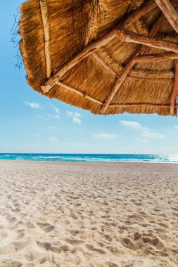 Sazdan güneş şemsiyesi altında sahilde görünümü