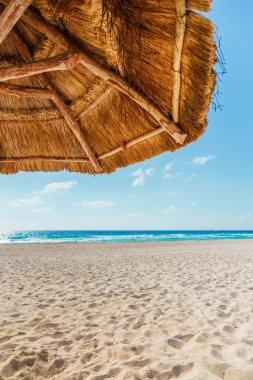 Sazdan güneş şemsiyesi altında sahilde görünümü