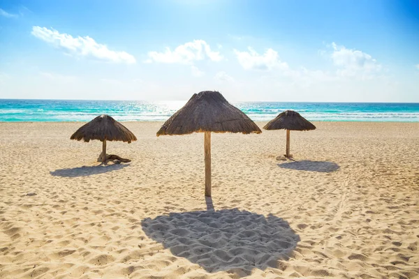 Playa vacía con tres sombrillas de paja — Foto de Stock