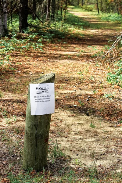 A trails closed sign with a path in the background.