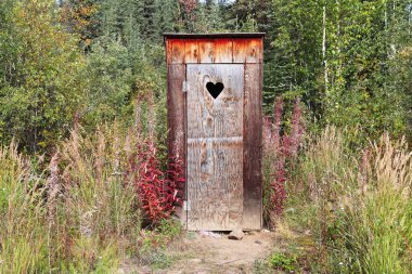 An outhouse in a wooded area with a heart window clipart