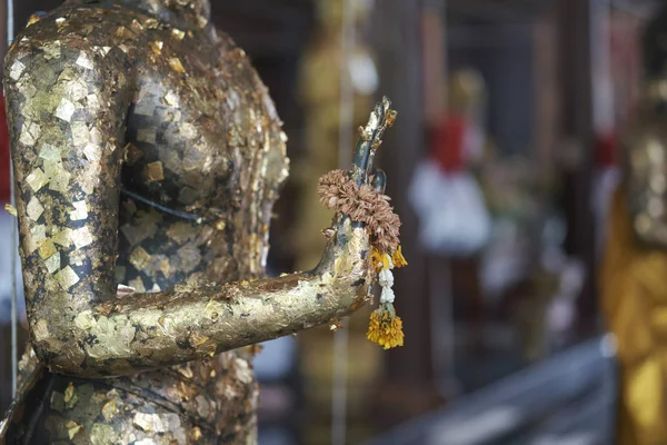 Attach gold leaf on hand Buddha statue and old Jasmine Wreaths o