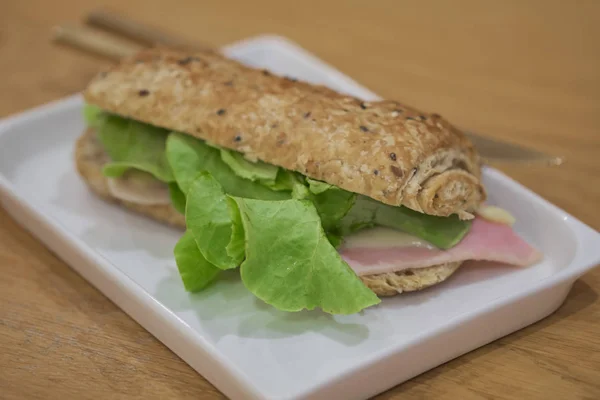 Delicioso sanduíche de presunto e queijo no prato branco — Fotografia de Stock